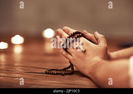 Person hands praying holding a rosary with cross of Christian faith, religion or tradition in a religious church closeup and background. Man Catholic Stock Photo