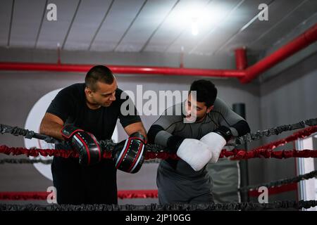 That was a good session. two young male athletes standing in a boxing ring after a sparring session. Stock Photo