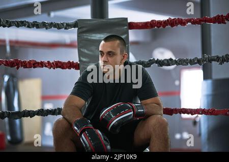 Getting familiar with the ring. a young male athlete sitting in the corner of a boxing ring. Stock Photo