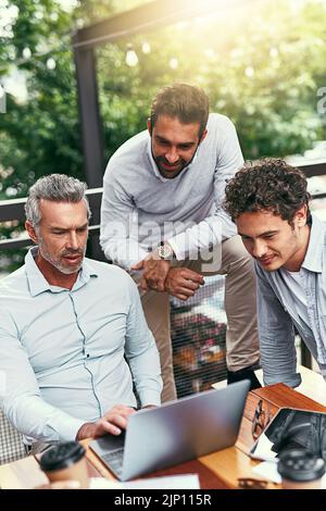Expert business knowledge times three. a team of colleagues using a laptop together during a meeting outdoors. Stock Photo
