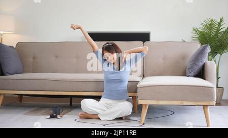 Work from home concept, Business women sit on floor and stretching to relax after working at home. Stock Photo