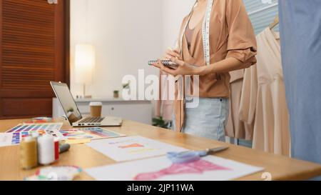 Fashion design concept, Asian female designer thinking new collection and sketching on notebook. Stock Photo