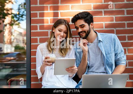Happy young couple working studying on laptop and digital devices. Business education people concept Stock Photo