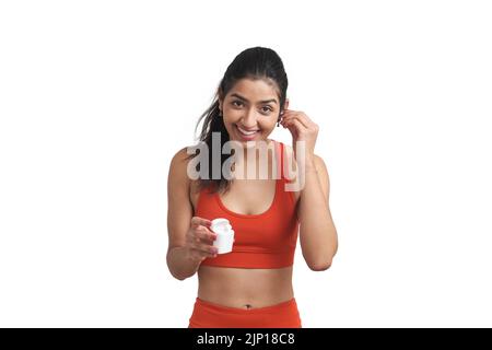 Young Venezuelan sportswoman smiling and wearing earphones, isolated. Stock Photo