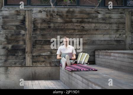 Focused man remote worker in eyewear working on laptop remotely outside. Outdoor workspace Stock Photo