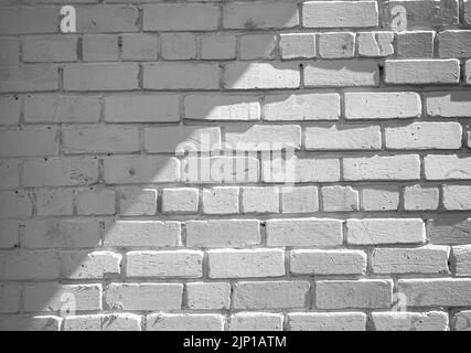 white brick wall is lit by the sun from side, an oblique shadow falls on the wall Stock Photo