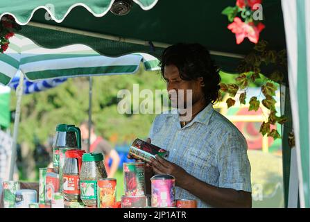 Young man Hindu street seller holding can in hands at his stall. July 12, 2018. Kyiv, Ukraine Stock Photo