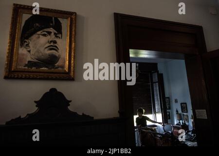 Forli, Italy. 10th Aug, 2022. A woman points to a uniform of former Italian dictator Benito Mussolin lying on his bed in the bedroom of his house in Forli. The house was bought from the Mussolini family at the turn of the millennium and turned into a private museum. Italy will elect a new government on Sept. 25, 2022, with Giorgia Meloni's post-fascist 'Fratelli d'Italia' party expected to win. (to dpa 'Italy's election favorite Meloni and fascism - 'worry is real'') Credit: Oliver Weiken/dpa/Alamy Live News Stock Photo