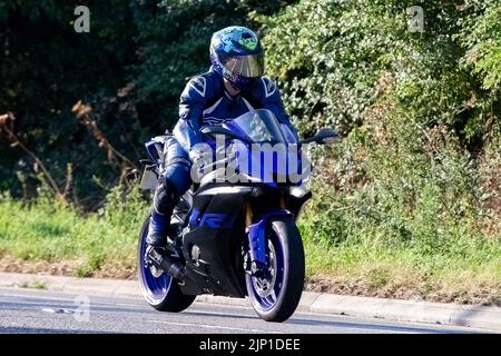 Man in blue leather riding a blue motorcycle Stock Photo