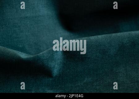 Dark green wrinkled fabric as a background close-up, fashion and trends, green background Stock Photo