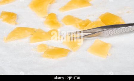 golden pieces of cannabis extract distillate and tweezers, high thc. Stock Photo