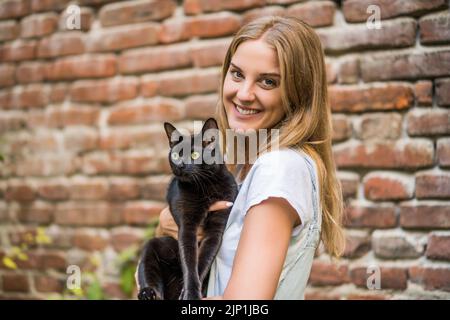 Woman and  her beautiful black cat  enjoy spending time together outdoor. Stock Photo