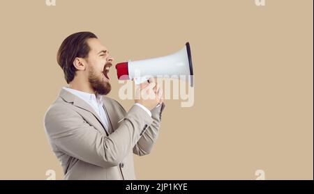 Businessman making job announcement and shouting through megaphone on copy space background Stock Photo