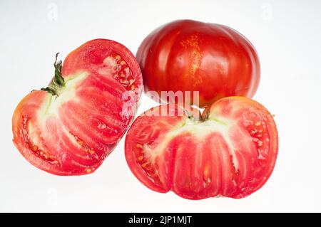 Two tomatoes- one large red ripe tomato cut in half Stock Photo