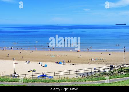 Glorious sunny blue sky calm August day on Tynemouth Long Sands with surfers canoes boarders and swimmers and families Stock Photo