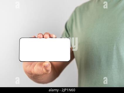 Man holding phone mockup in horizontal position. Person using smartphone for showing video or photo. Android with white display. High quality photo Stock Photo