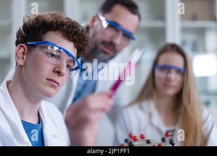 Science students with teacher doing chemical experiment in the laboratory at university. Stock Photo