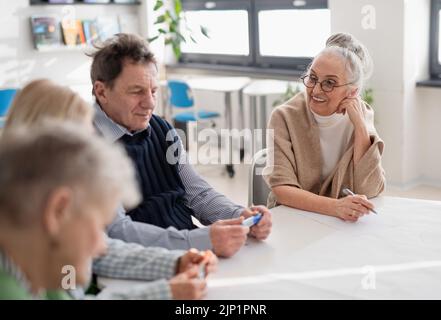 Group of senior students discussing about altenrative energy in classroom, close-up. Stock Photo