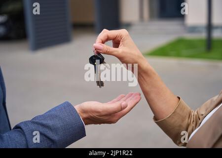 Female hand puts in male palm keys to new house Stock Photo