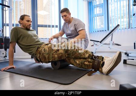 Patient doing special rehabilitation exercises under supervision of instructor Stock Photo