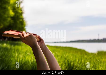 Women hands holding a book with forest in background Stock Photo