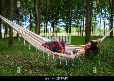 Beautiful young woman relaxing on hammock in the forest Stock Photo