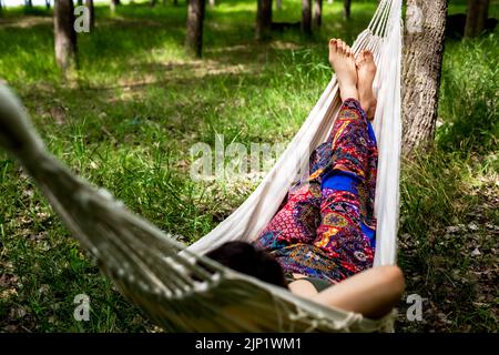 Young women relaxing in the forest laying on hammock Stock Photo