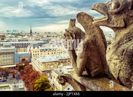 Gargoyle on Notre Dame de Paris Cathedral, France. Medieval gargoyles (chimera) are landmark of Paris. Panorama of Paris and old demon statues on roof Stock Photo