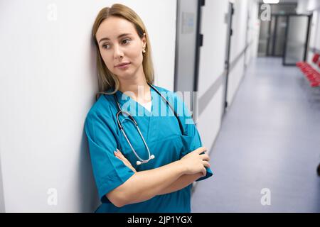 Adult lady is standing in the hallway wearing a blue doctor uniform in the hallway Stock Photo