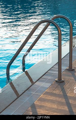 Swimming pool with stair and wooden deck at hotel. Stock Photo