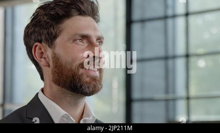 Close up successful pensive puzzled dreaming contemplating man Caucasian thoughtful adult mature 40s businessman looking out window thinking idea Stock Photo