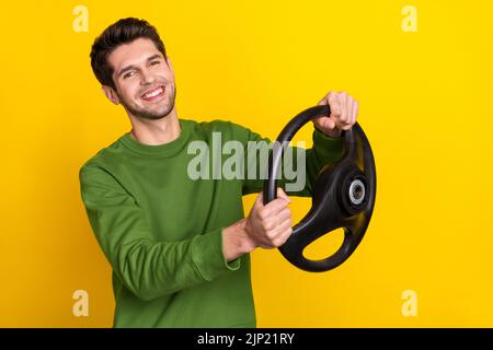 Portrait of attractive cheerful guy holding steering wheel riding isolated over vivid yellow color background Stock Photo
