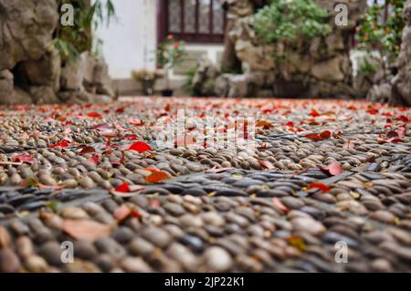 Autumn leaves on a cobble stone pathway in a chinese garden Stock Photo