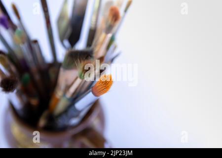Artist's workplace. Different size and quality artistic brushes in ceramic jug. Stock Photo