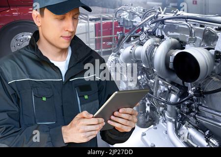 Mechanic repairing the truck engine in the garage using digital tablet Stock Photo