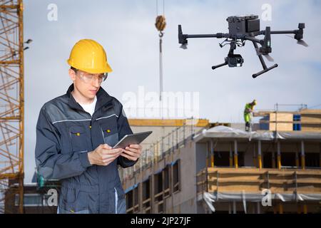 Engineer with digital tablet controls drone on a construction site Stock Photo