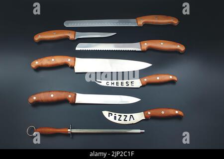 Quality Kitchen Knives. Set of various kitchen knives arranged on black, top view. Stock Photo