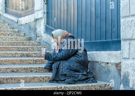 Roma women on bridge in Venice begging holding out cup and begging for money Stock Photo