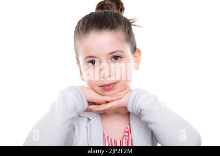 A portrait of a young girl posing with her hands under her chin against a white background Stock Photo