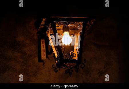 A closeup shot of a dusty lamp hanging from above in darkness Stock Photo