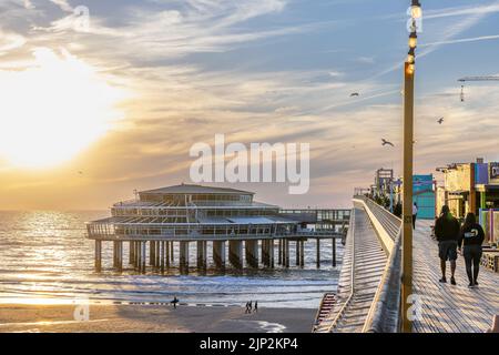 A beautiful view of people walking on the Scheveningen de Pier during sunset Stock Photo