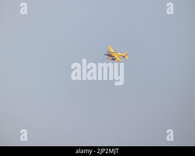 A small yellow hydro plane for fire extinction flying to pour water on a fire and thus put it out with deep blue sky on background Stock Photo