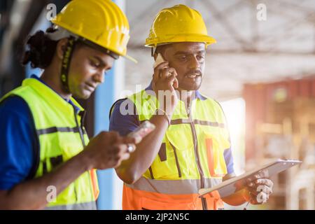Indian Engineer worker foreman using telephone calling communication and technology device in factory workplace Stock Photo