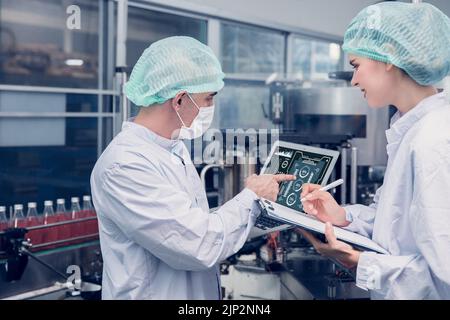 Food and Drink factory worker working together with hygiene monitor control mix ingredients machine with laptop computer Stock Photo