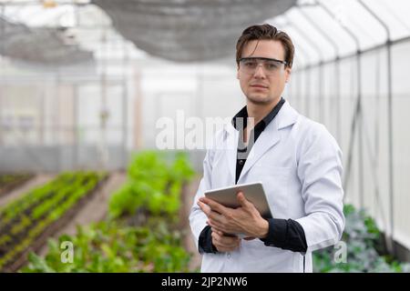Portrait Scientist male researcher staff worker collecting study plant information in agriculture farm. Agricultural Science concept. Stock Photo
