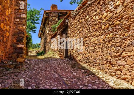 Narrow cobbled street with rustic stone houses and old and medieval atmosphere. Stock Photo