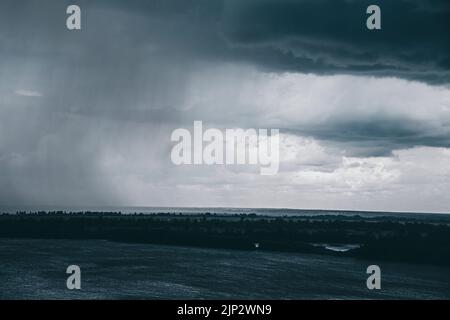 Rain clouds. Storm clouds sky rolling. Storm clouds with pouring rain over a river Stock Photo