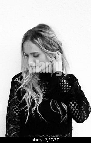 A vertical shot of a beautiful young woman looking down and playing with her hair Stock Photo