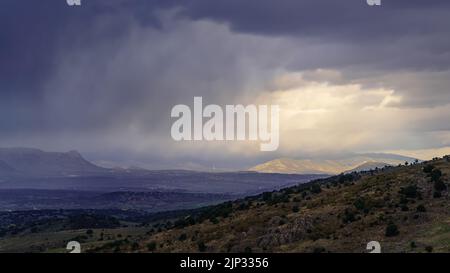 Dramatic storm sky landscape with sun rays between the clouds and over the mountains. Dark landscape. Madrid. Stock Photo