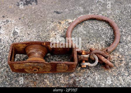 Old rusting steel winch pulley and ring at a coastal harbour location Stock Photo
